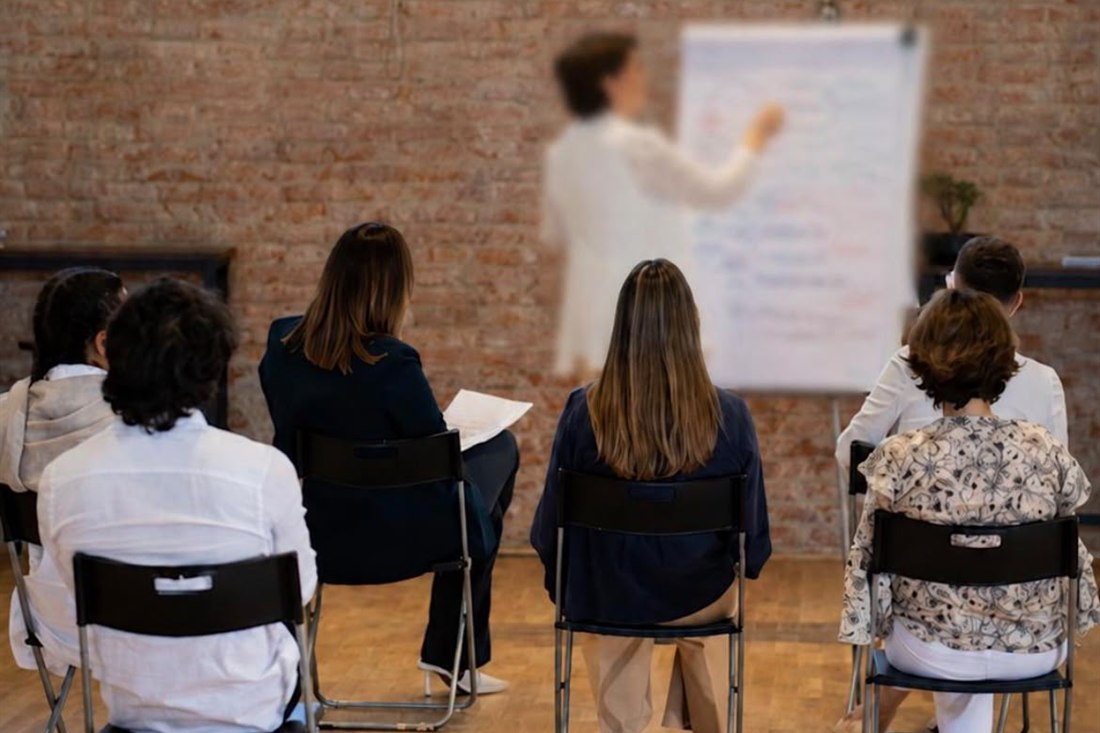 Formatrice alla lavagna a fogli mobili davanti a un gruppo in aula